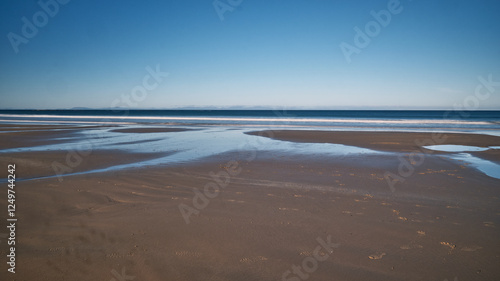 The image captures a serene, ethereal seascape bathed in a soft, dreamy light. Smooth, flowing waves gently undulate across the frame.