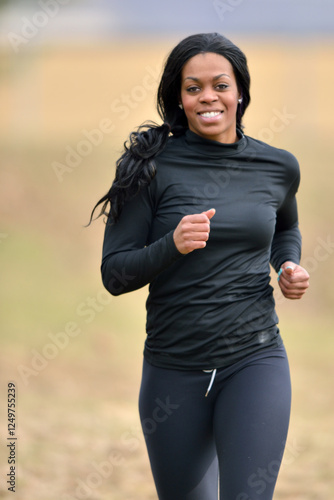 Attractive young African American woman jogs in black leggings and long sleeve shirt (winter)
