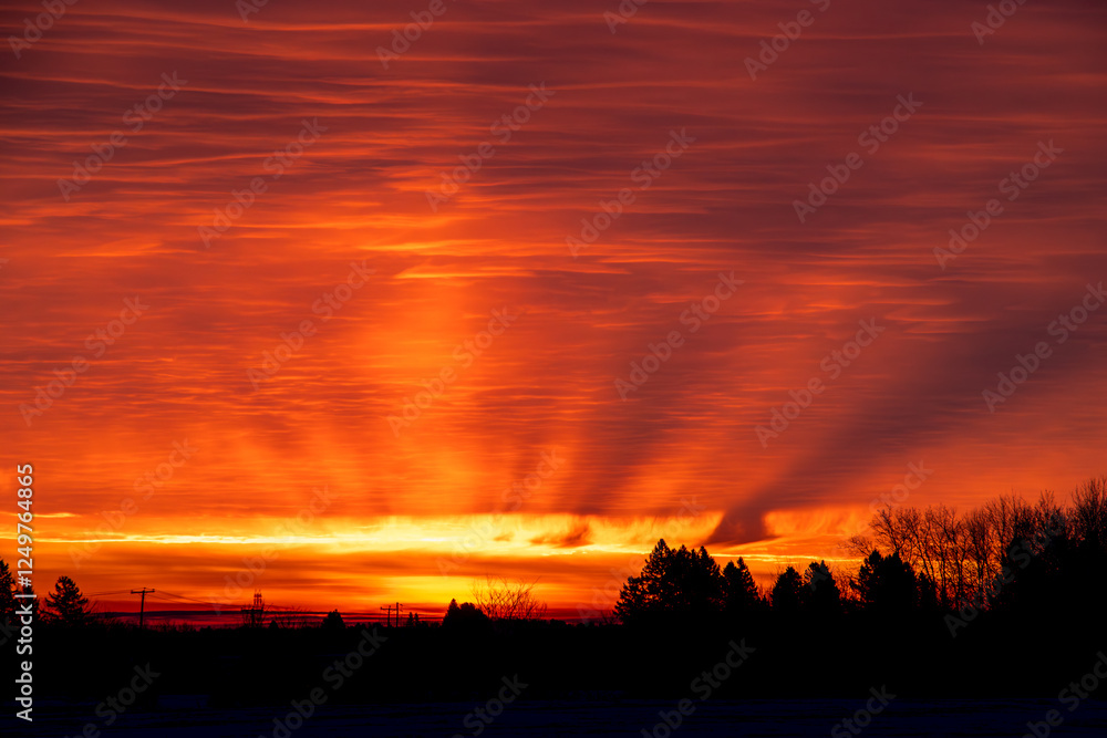 Fototapeta premium Red sunrise with sun beams coming through the clouds.