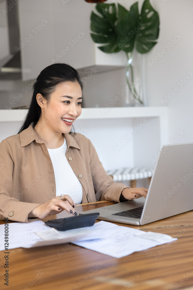 Happy successful Asian financial specialist woman typing on laptop and calculator at home, counting income from investment, savings, using accounting application at computer, smiling. Vertical shot Happy successful Asian financial specialist woman typing on laptop and calculator at home, counting income from investment, savings, using accounting application at computer, smiling. Vertical shot