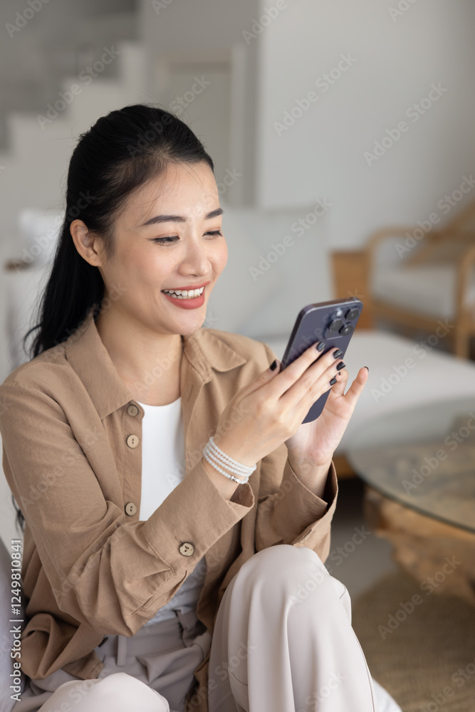 Cheerful young Asian woman chatting on mobile phone, using online modern technology, smart home application on cell phone, smiling, laughing, enjoying leisure with media service Cheerful young Asian woman chatting on mobile phone, using online modern technology, smart home application on cell phone, smiling, laughing, enjoying leisure with media service