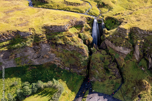 A magnificent aerial view Gljufrabui waterfall in Iceland plunges over the edge of green cliffs, surrounded by stunning countryside. The serene landscape captures beauty of untouched nature