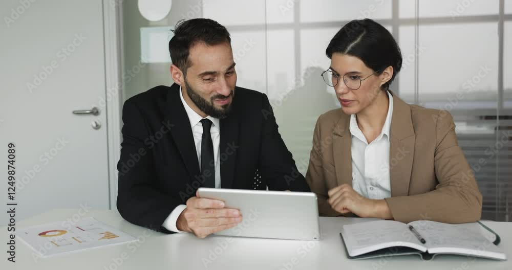 Two professionals lively discussing project details or updates seated at table, identifying trends, review new business tool or software using digital tablet device. Mentor explain tasks to colleague Two professionals lively discussing project details or updates seated at table, identifying trends, review new business tool or software using digital tablet device. Mentor explain tasks to colleague