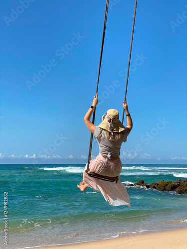 female traveller in a dress and wide-brimmed hat on a swing
