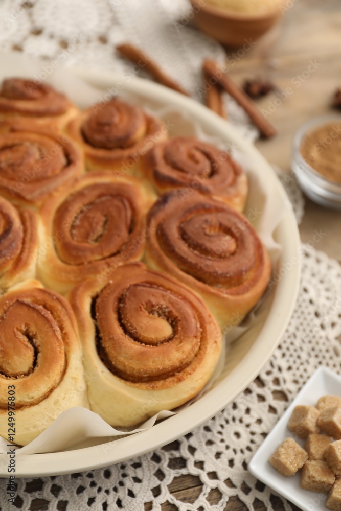 Freshly baked cinnamon rolls and brown sugar cubes on table, closeup Freshly baked cinnamon rolls and brown sugar cubes on table, closeup