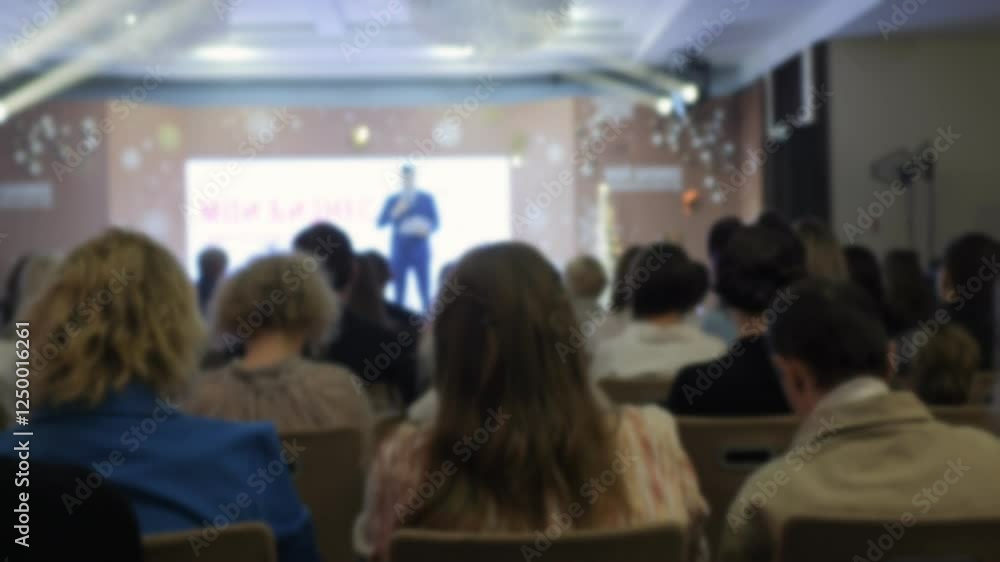 Man is giving a speech in front of a large audience. The audience is attentive and engaged, listening to the speaker. The speaker is using a microphone to amplify his voice Man is giving a speech in front of a large audience. The audience is attentive and engaged, listening to the speaker. The speaker is using a microphone to amplify his voice