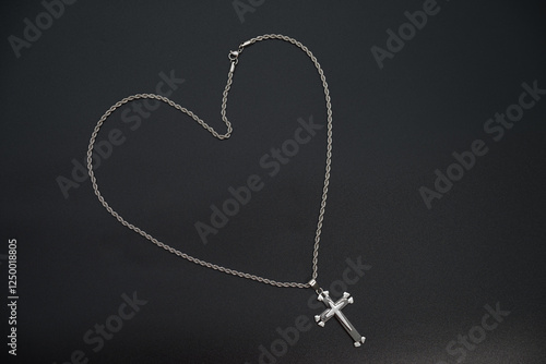 a silver chain with a cross on a black background