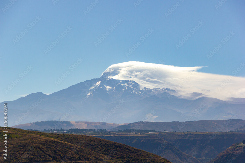 Fototapeta premium Vista del volcán Cayambe en día despejado y soleado, se aprecia nubes sobre la cima.