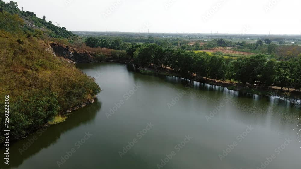 Green landscape with a calm lake, rocky hills, and farmland in Tay Ninh, Vietnam Green landscape with a calm lake, rocky hills, and farmland in Tay Ninh, Vietnam