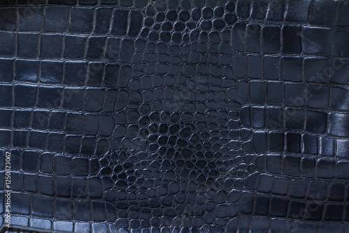 Close-up view of a deep navy crocodile embossed leather texture.