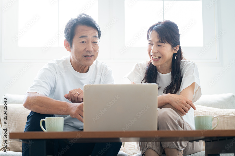 パソコンを見ながら会話する50代夫婦