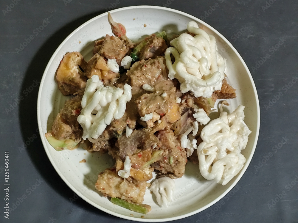 Rujak Cingur. Traditional Javanese food consisting of lontong with vegetables, peanut sauce, petis, tempeh, tofu, beef tongue, and crackers. Rujak Cingur. Traditional Javanese food consisting of lontong with vegetables, peanut sauce, petis, tempeh, tofu, beef tongue, and crackers.