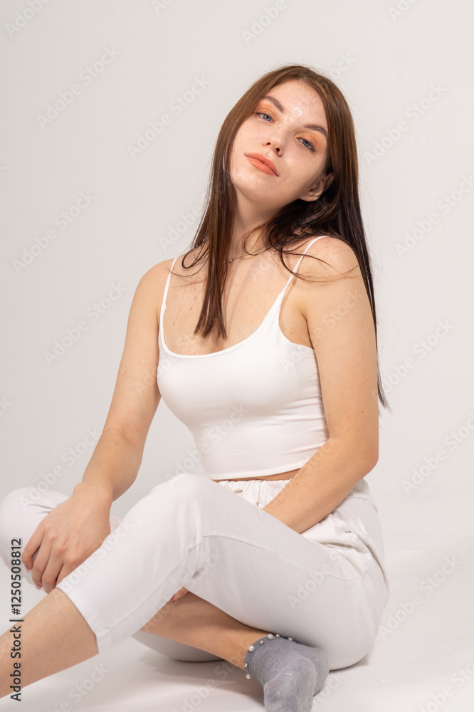 Young brunette sitting on a white background. Copyspace Young brunette sitting on a white background. Copyspace