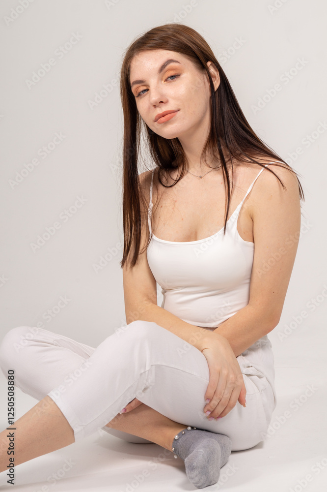 Young brunette sitting on a white background. Copyspace Young brunette sitting on a white background. Copyspace