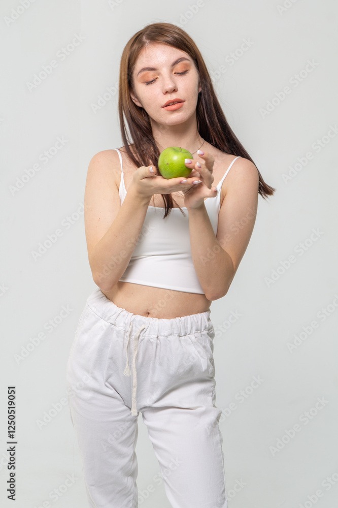 Young brunette holding a green apple standing on a white background. Copyspace Young brunette holding a green apple standing on a white background. Copyspace