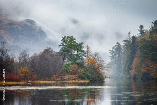 Misty moody autumn morning with colorfull trees and mountain reflecting in a lake, Loch Trool, Scotland