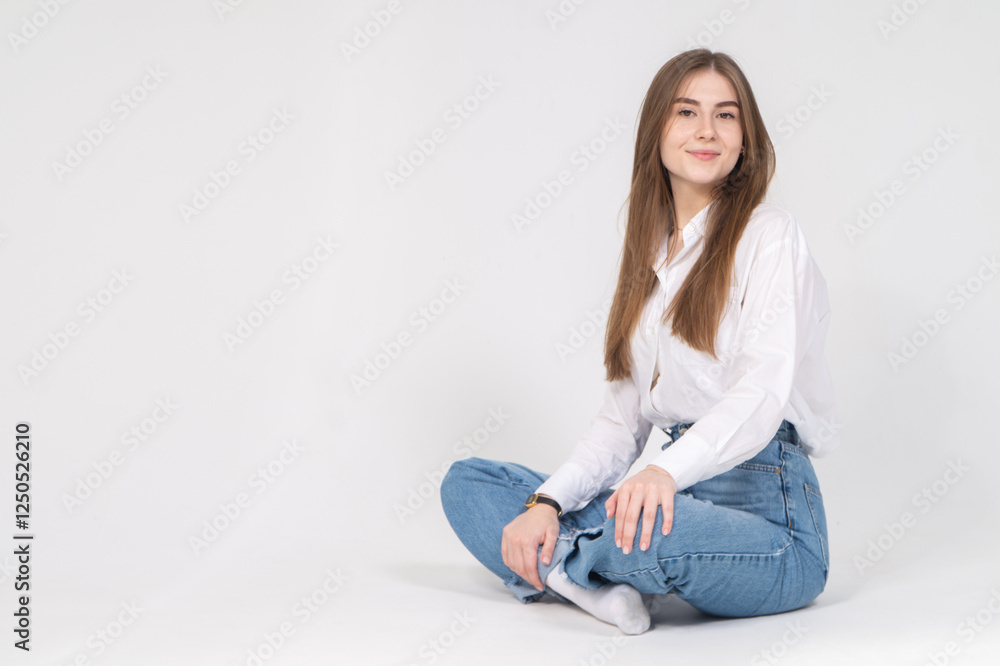 Cute young girl sitting on a floor, white background, copyspace Cute young girl sitting on a floor, white background, copyspace
