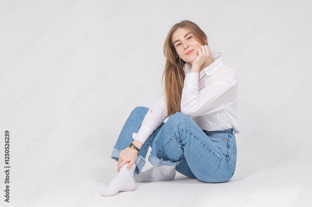 Cute young girl sitting on a floor, white background, copyspace Cute young girl sitting on a floor, white background, copyspace