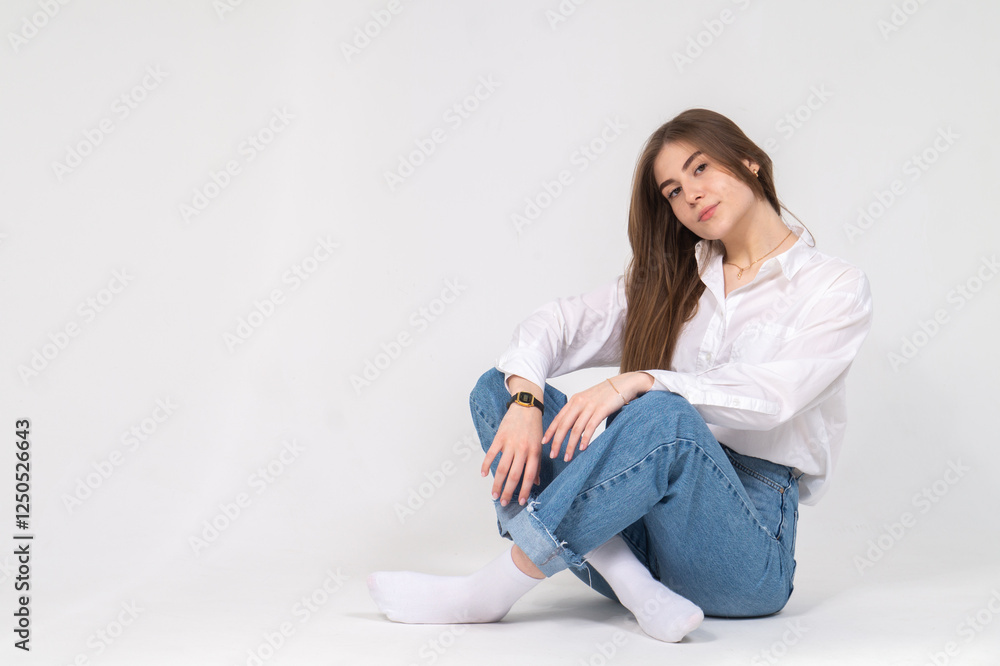 Cute young girl sitting on a floor, white background, copyspace Cute young girl sitting on a floor, white background, copyspace