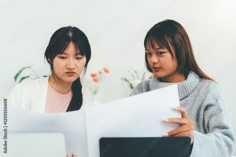 Female higher education student using laptop and studying book in home, Online learning. Female higher education student using laptop and studying book in home, Online learning.