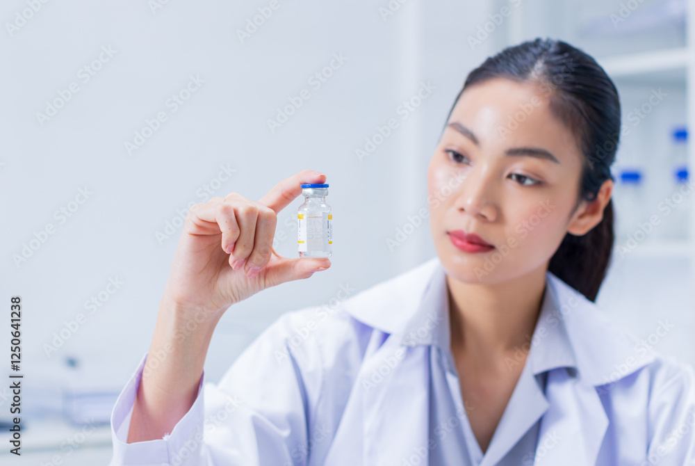 Asian professional female scientist, medical woman researcher with Vaccine Ampoule examining testing at laboratory. Woman doctor looking at blood test tube working on vaccination development. Asian professional female scientist, medical woman researcher with Vaccine Ampoule examining testing at laboratory. Woman doctor looking at blood test tube working on vaccination development.