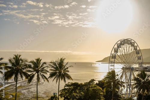 Quadro su tela Golden hour over the ferris wheel, treetops, lagoon and hilly backdrop of Cairns