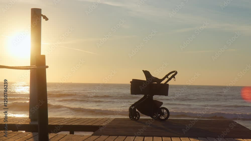 Baby pram on a beach promenade at sunset. Happy childhood Baby pram on a beach promenade at sunset. Happy childhood