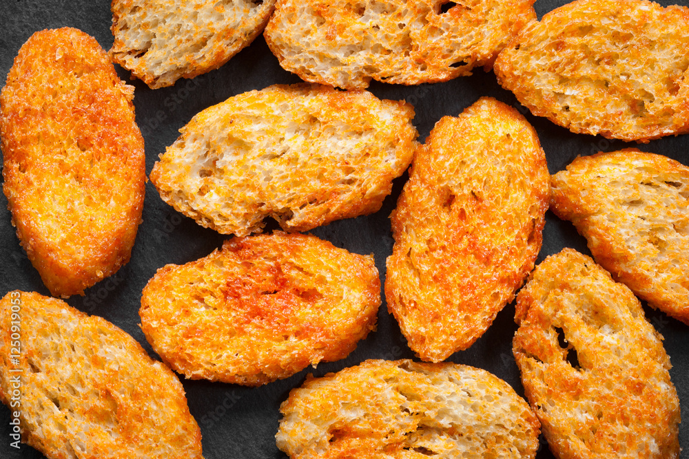 Rusks with spices. Fried croutons. Top view. Croutons on a dark Rusks with spices. Fried croutons. Top view. Croutons on a dark