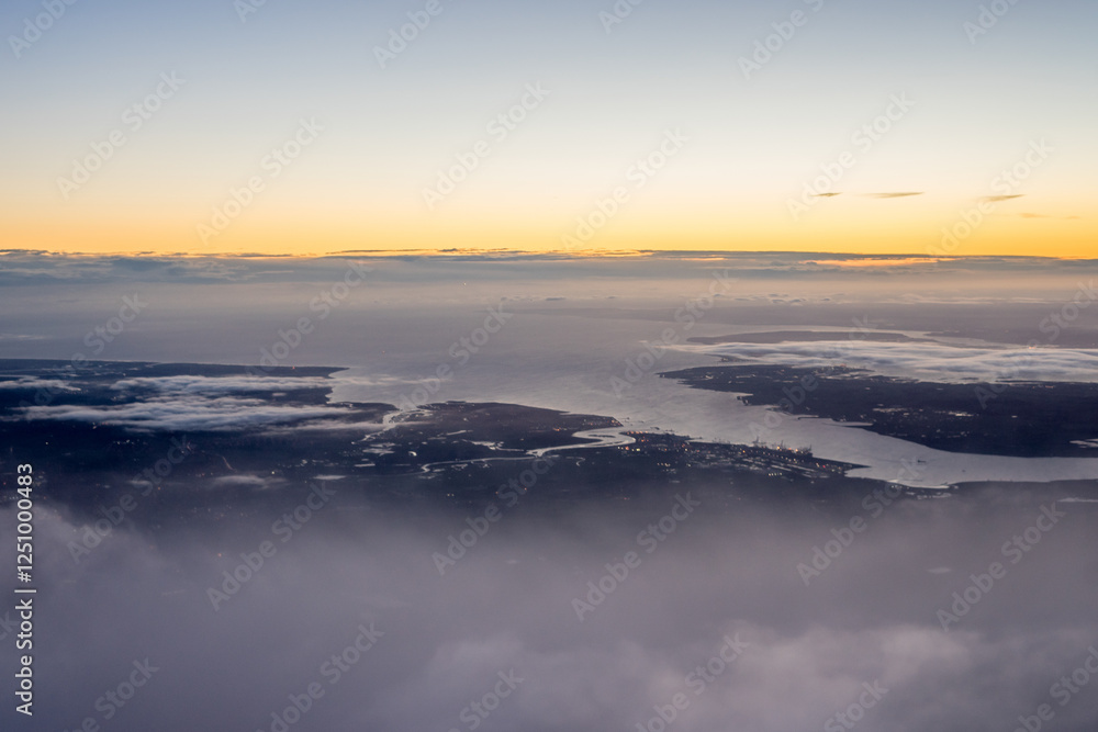 Aerial view of London through early morning clouds with Thames river flowing at golden hour sunrise