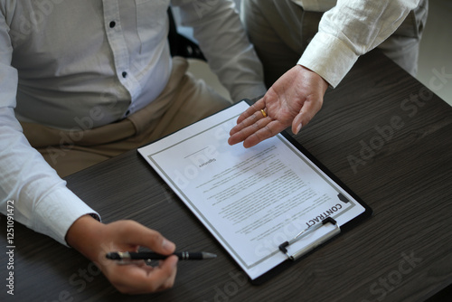 An asian insurance agent visiting client's home selling policy scheme and successful deal, showing the place to sign the contract and shaking hands together celebrating finished contract.