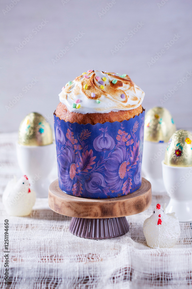Easter cake, chocolate eggs in gold foil and chicken-shaped candles on a light background.