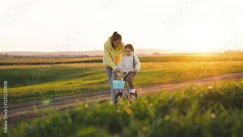 Wallpaper Mural A woman is helping a child ride a bike. The scene is set in a grassy field with a beautiful sunset in the background. Scene is peaceful and heartwarming, as the woman and child share a special moment Torontodigital.ca