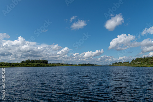 river with small waves in summer cloudy blue sky and trees on the banks of the Daugava