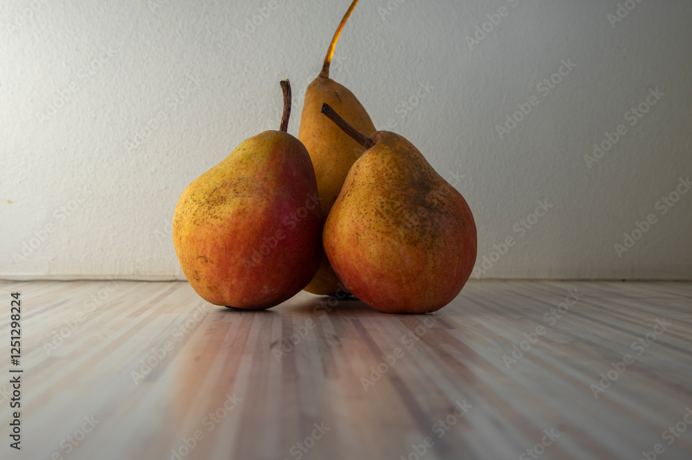 Three pears edible fruits, tasty ripened red yellow fruit on wooden background