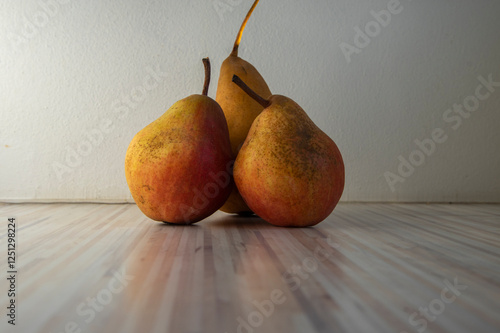 Obraz na płótnie Three pears edible fruits, tasty ripened red yellow fruit on wooden background w salonie