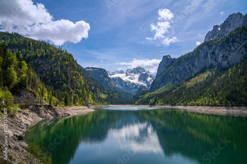 Lake Gosau or Gosausee, Gosaukamm and Mount Dachstein. Panoramic landscape with mountains, glacier and green forest in Austrian Alps, Upper Austria, Europe. Sunny day, spring