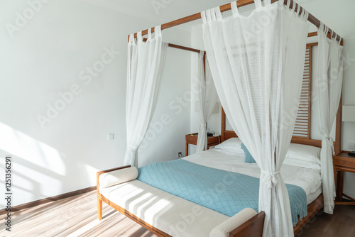 Obraz na plátně Simple and elegant bedroom with a canopy bed, draped with light white curtains that add a sense of airiness and tranquility
