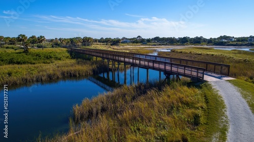 Wallpaper Mural A serene landscape featuring a wooden bridge over a calm waterway, surrounded by lush greenery and clear blue skies. Torontodigital.ca