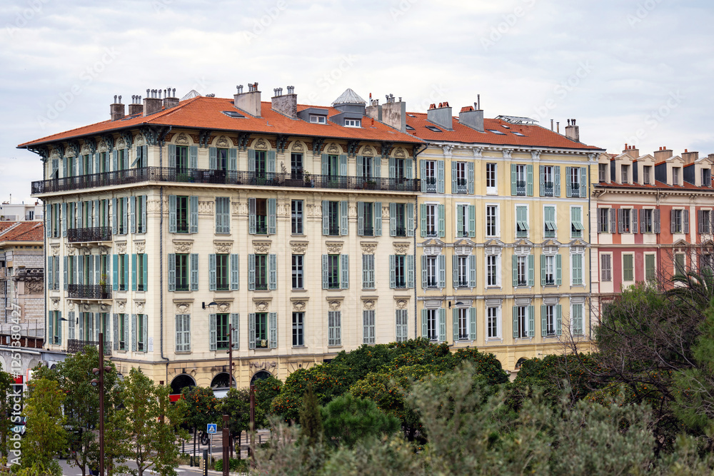 Red and orange buildings in Nice, France, park with green park trees Red and orange buildings in Nice, France, park with green park trees