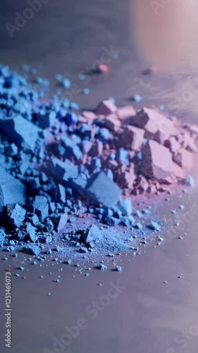 A close-up of crushed, colorful makeup powders in shades of blue, red, pink, and gold.