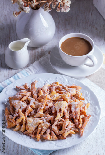 Traditional Maslenitsa dessert angel wings served with coffee on a light background.