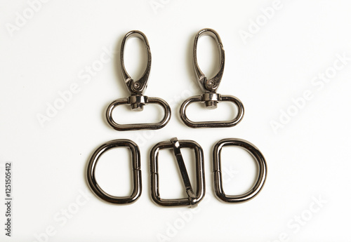 A set of black chrome swivel hooks, D rings and a buckle for bag accessories, isolated on white.