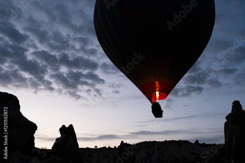 Hot air balloon is on the air at Cappadocia. Silhouette photo at sunrise.