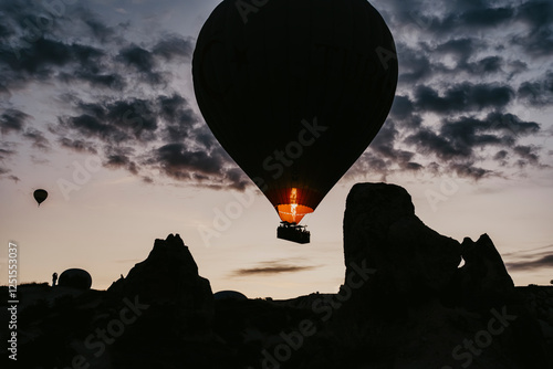 Hot air balloon is on the air at Cappadocia. Silhouette photo at sunrise.