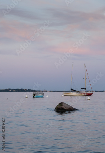 Boats moored on Garda lake under a pinky sky at sunset photo