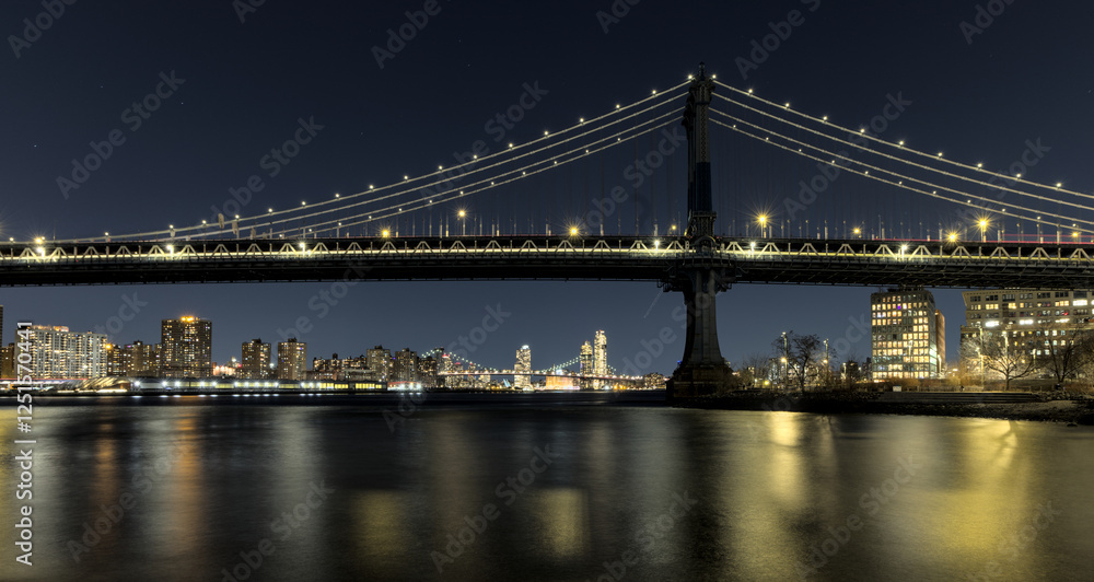 Naklejka premium manhattan bridge detail long exposure at night with east river reflections and williamsburg bridge in the background (train passing walkway overpass) dumbo brooklyn travel tourism usa nyc landmark