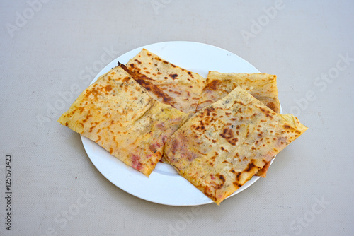 Freshly baked appetizing Turkish tortillas - Gozleme with spinach, cheese  on a white board. Space for text. Handmade Turkish traditional pastries. Ispanakli, otlu peynirli gozleme. Tahinli Katmer photo