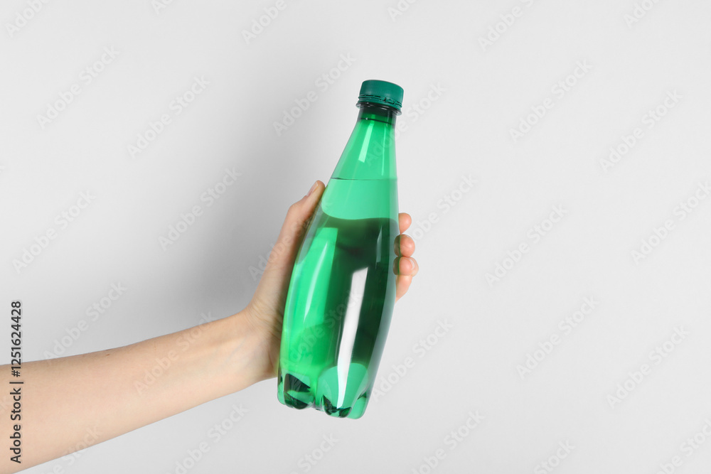 Woman holding plastic bottle of water on light background, closeup Woman holding plastic bottle of water on light background, closeup