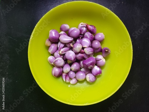 Photos A pile of red onions in a green plastic container seen from close up