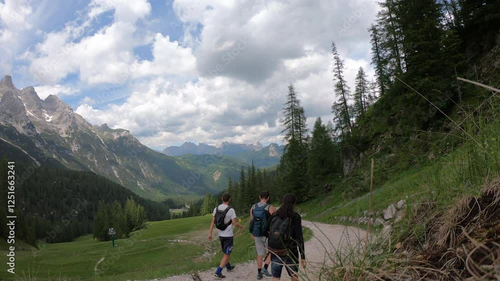 Hikers enjoy the tranquility of a forest trail, surrounded by dense greenery and glimpses of towering Dolomite cliffs. Hikers enjoy the tranquility of a forest trail, surrounded by dense greenery and glimpses of towering Dolomite cliffs.